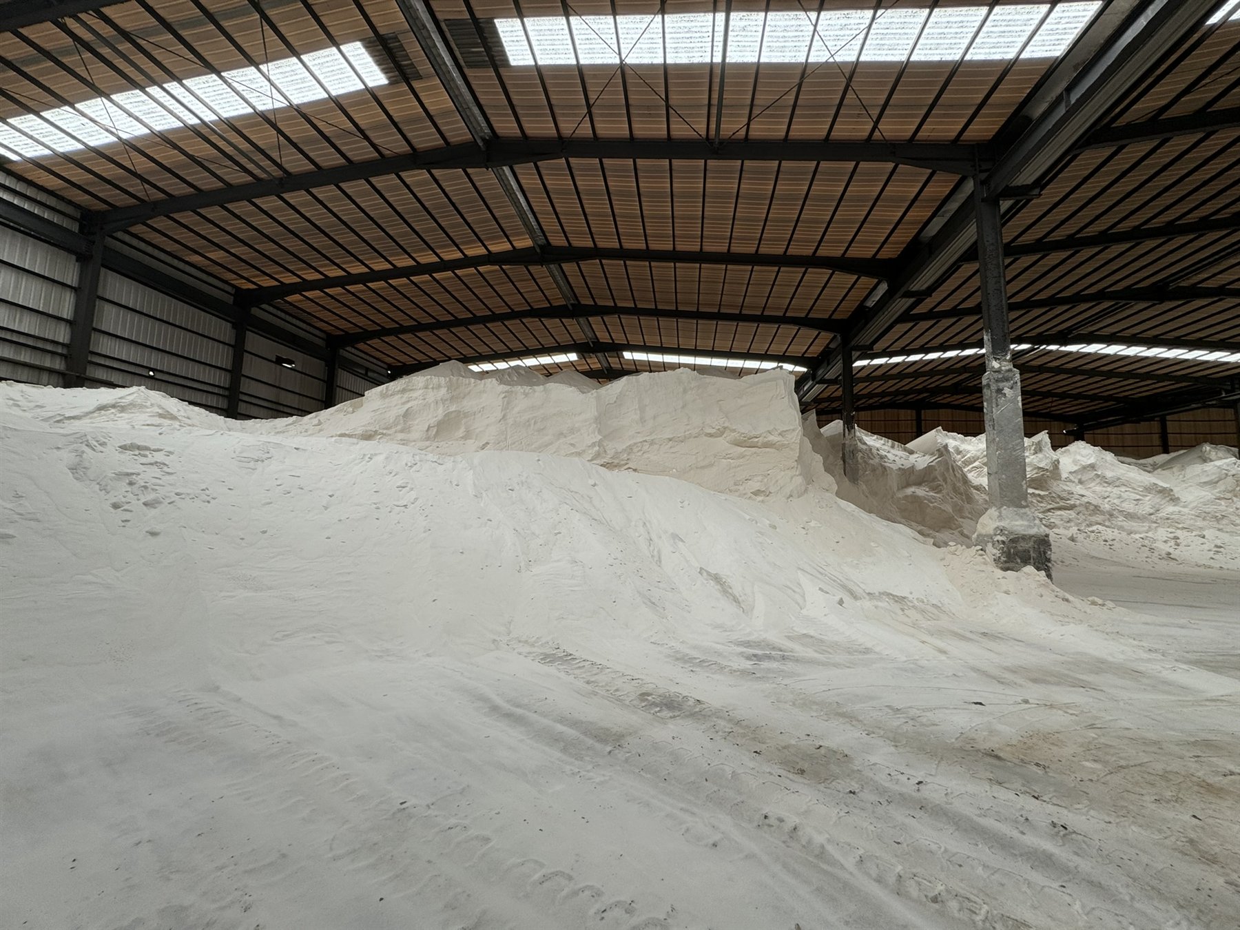 Bulk white fertilizer material stored inside a covered warehouse